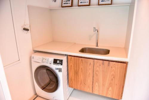 a small kitchen with a sink and a washing machine at Casa João de Barro - Praia de Guaecá in Barequeçaba