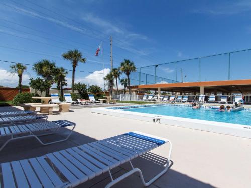 una piscina con panchine blu e palme di Surf Dweller 703 a Fort Walton Beach