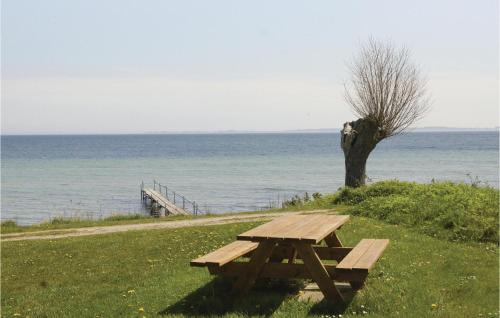 a wooden picnic table sitting next to the ocean at Four-Bedroom Holiday Home In Hesselager in Hesselager