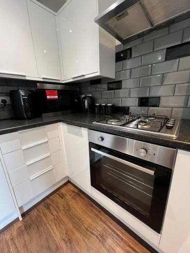 a kitchen with white cabinets and a stove top oven at Fully ensuite room in Hull