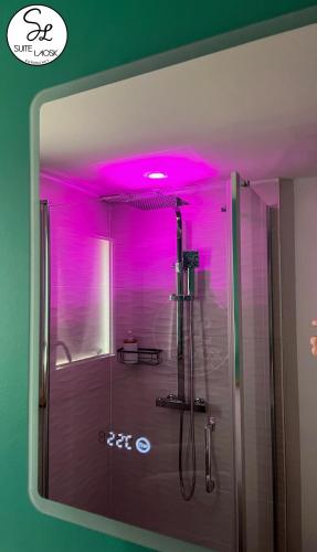 La salle de bains est pourvue d'une douche avec un éclairage rose. dans l'établissement Suite Laosk, à Pornichet