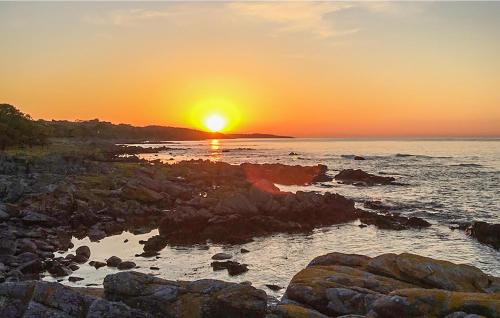 a sunset over the ocean with rocks in the foreground at Gorgeous Home In Svaneke With Wifi in Svaneke