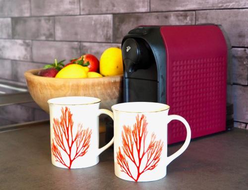 two coffee mugs next to a toaster and a bowl of fruit at Ferienwohnung Margarethe in Velden am Wörthersee