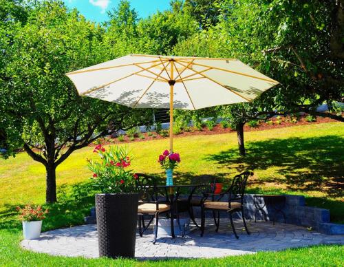 a table and chairs under an umbrella in a garden at Ferienwohnung Margarethe in Velden am Wörthersee