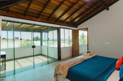 a bedroom with a blue bed and glass walls at Casa de Praia c/ Piscina e Área Gourmet | AGV 1 in Fazendinha