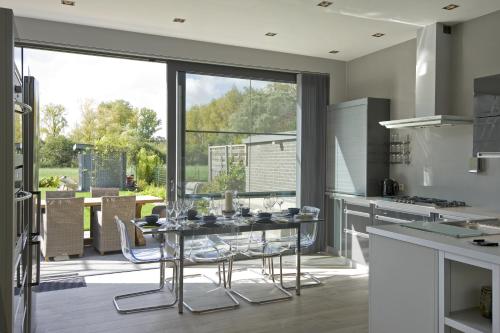 a kitchen with a glass table and some chairs at Aan Den Oever Logies in Korbeek-Dijle