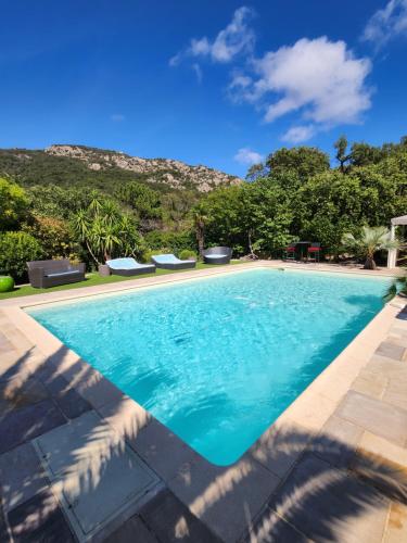 une piscine avec de l'eau bleue et des montagnes en arrière-plan dans l'établissement Demeure raffinée et exceptionnelle dans un cadre de vacances idéal à l'ombre des pins parasols, au Plan-de-la-Tour