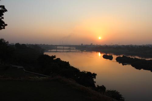 a view of a river at sunset with the sun setting at Brijraj Bhawan Palace Hotel in Kota