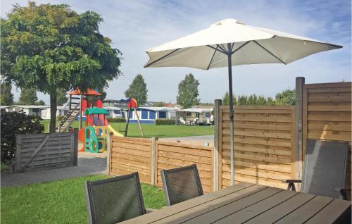 a table with an umbrella next to a playground at 2 Bedroom Amazing Home In Groede in Groede
