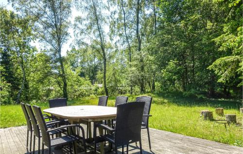 a wooden table and chairs on a deck with a garden at 3 Bedroom Lovely Home In Rønne in Rønne