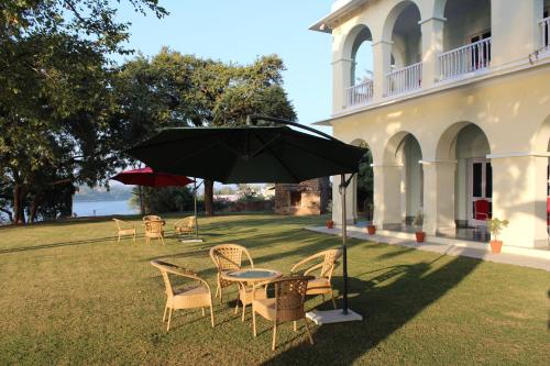 a table and chairs with an umbrella in the grass at Brijraj Bhawan Palace Hotel in Kota