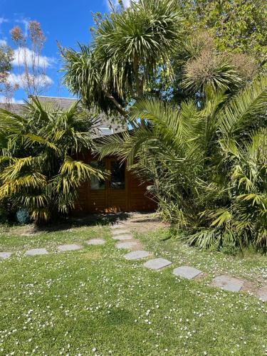 une maison avec des palmiers en face d'une cour dans l'établissement Chalet dans jardin privatif, à Caen