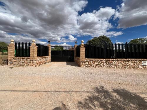 a black fence with a stone wall and a gate at Villa Tranquila Lagunas de Ruidera in Ossa de Montiel