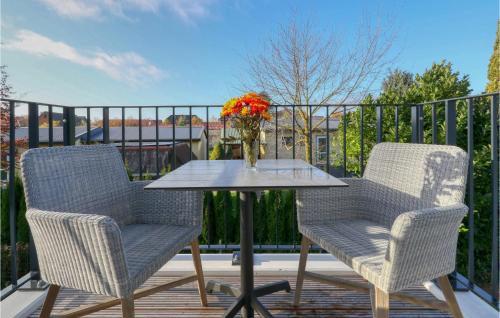 2 Stühle und ein Tisch mit einer Vase Blumen auf dem Balkon in der Unterkunft Baltischer Hof Apartment 30 in Boltenhagen