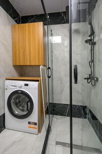 a washing machine in a bathroom with a shower at Azur Properties 56 in Shkorpilovtsi