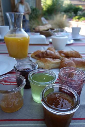 a table topped with different types of food and a jug of orange juice at Maison Addama in Neyron