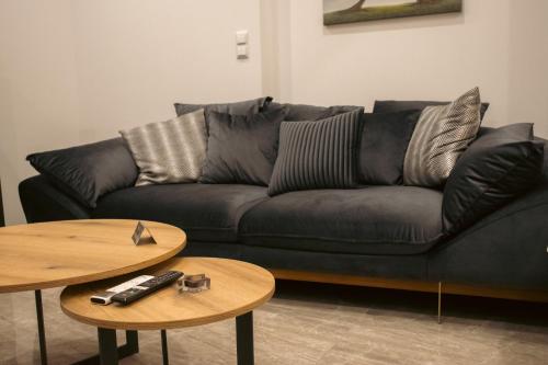 a living room with a black couch and two tables at Emily Apartments 2 in Chrysoupolis