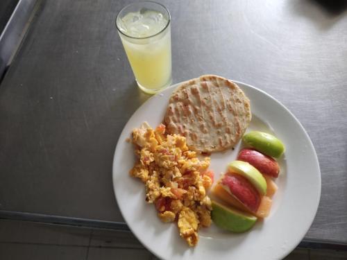 a plate of food with bread and fruit and a glass of orange juice at Hotel El Bosque Valledupar in Valledupar