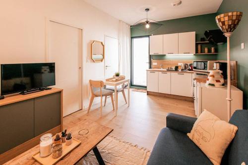 un salon avec un canapé et une cuisine dans l'établissement Bel appartement neuf et paisible, à La Chapelle-des-Fougeretz