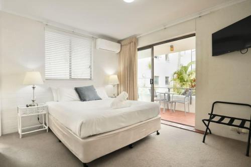 a white bedroom with a bed and a balcony at Beach Lovers Dream 2BR in Noosa Heads