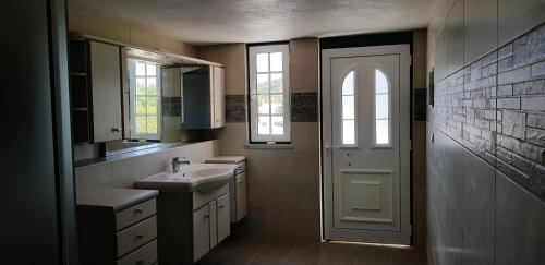 a bathroom with a sink and a white door at Solar Rubina - Piscina Água Salgada in Belmonte