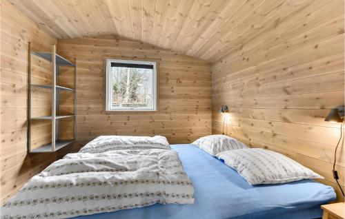 two beds in a room with wooden walls and a window at Five-Bedroom Holiday Home In Blokhus in Blokhus