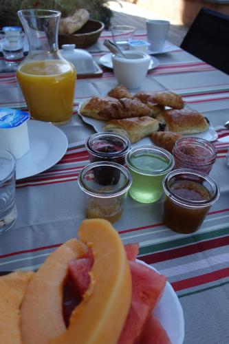 a table topped with plates of food and orange juice at Maison Addama in Neyron