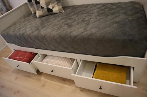 un lit avec des tiroirs blancs et un cadre de lit dans l'établissement Maisonnette au porte des vignes, à Gradignan