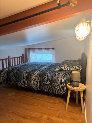 une chambre avec un lit et une table avec une lampe dans l'établissement Petite maison cosy en bord de Marne 2 lits en mezzanine, à Maisons-Alfort