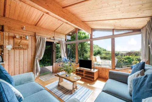 a living room with a blue couch and a tv at Scandinavian Style Lodge in Rock in Wadebridge