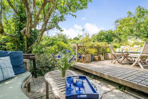 un patio avec une terrasse en bois dotée d'une table et de chaises dans l'établissement Scandinavian Style Lodge in Rock, à Wadebridge