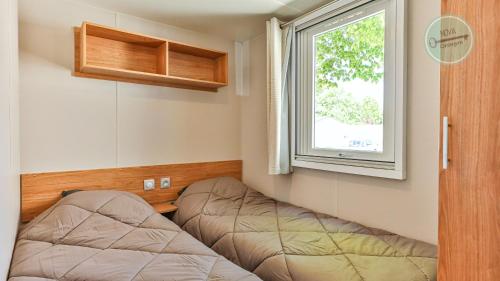 Cette chambre comprend 2 lits et une fenêtre. dans l'établissement Le Bois Masson 130 by Nova, à Saint-Jean-de-Monts