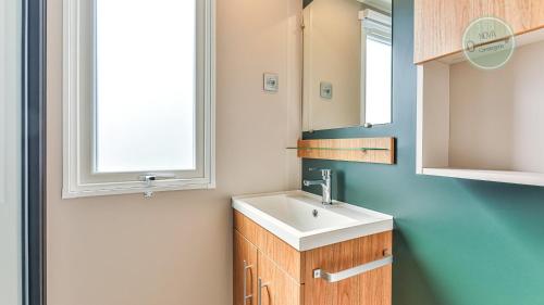 une salle de bain avec un lavabo et deux fenêtres dans l'établissement Le Bois Masson 130 by Nova, à Saint-Jean-de-Monts