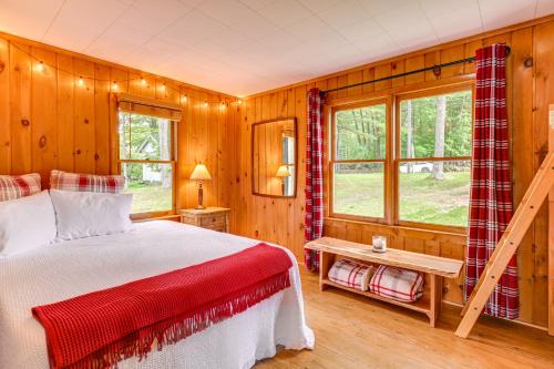 a bedroom with a bed and wooden walls and windows at Hale Rustic Retreat on Long Lake Near Boat Launch! in Hale