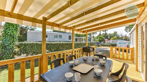 un patio avec une table et des chaises sur une terrasse dans l'établissement Le Bois Dormant 761 by NOVA, à Saint-Jean-de-Monts