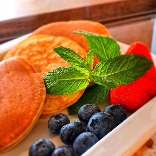 a plate of fruit with strawberries and blueberries and mint at Hotel & Wellness Fra I Pini in Lignano Sabbiadoro