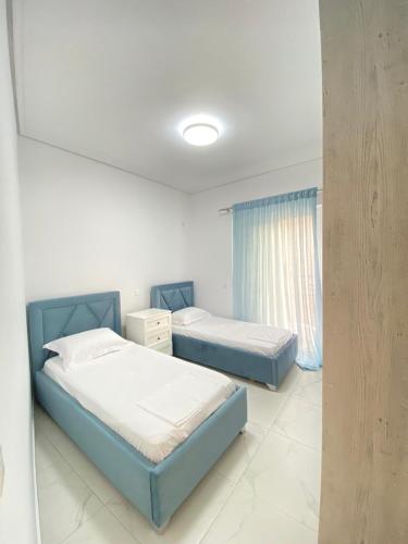 Valbona Apartment في سارنده: غرفة نوم بها سريرين ونافذة