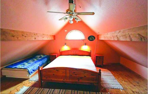 a attic bedroom with a bed and a ceiling fan at Awesome Home In Annerstad With Sauna in Romborna