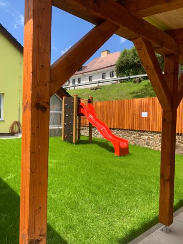 a playground in a yard with a red slide at Penzion Pod pecí in Lenora