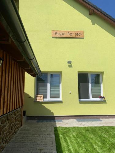 a yellow building with a sign on the side of it at Penzion Pod pecí in Lenora
