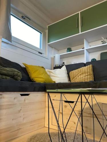 a couch with pillows on it in a living room at Tiny House à Champdray La Ty Vosg'Breizh in Champdray