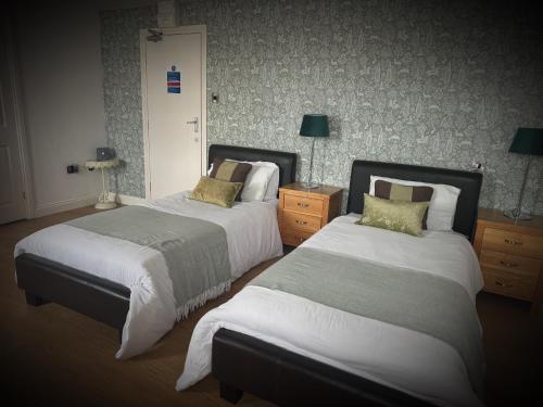a hotel room with two beds and two lamps at Ivy By The Sea in Scarborough