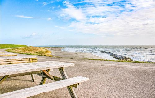 a row of wooden benches sitting next to the ocean at Stunning Home In Heinkenszand With Wifi in Heinkensand