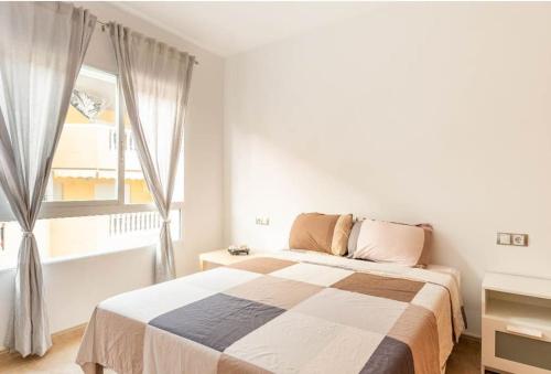 a white bedroom with a bed and a window at Lindo y Discreto apartamento playa in Moncófar