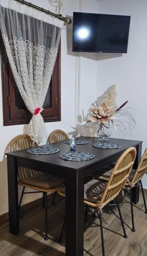 a black dining room table with chairs and a tv at Kontili house in Skiros