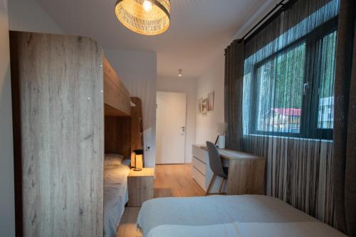 a bedroom with a bed and a desk and a window at Hyggemate - Nordic Villa with Sauna & Jacuzzi Retreat in Sarnitsa