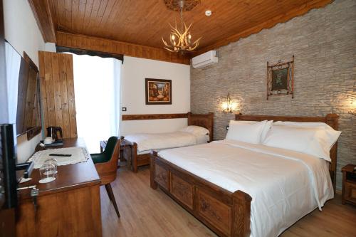 a bedroom with two beds and a desk and a television at City Street Hotel in Gjirokastër