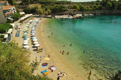 a beach with umbrellas and people in the water at Studios Nelli Alonissos in Patitiri