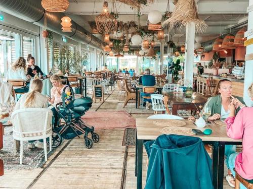 a group of people sitting at tables in a restaurant at Houseboat in Offingawier with Sea View in Offingawier