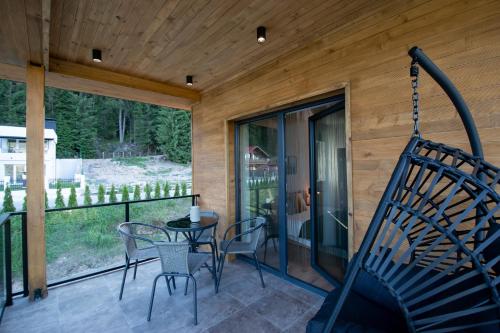 a porch with a swing and a table and chairs at Hyggemate - Nordic Villa with Sauna & Jacuzzi Retreat in Sarnitsa